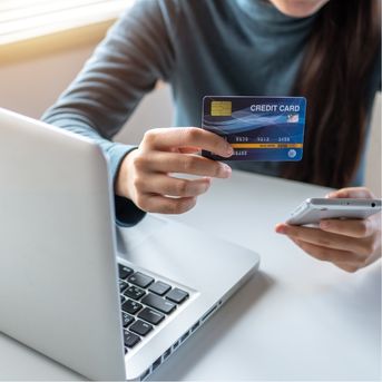 Woman holding credit card at laptop
