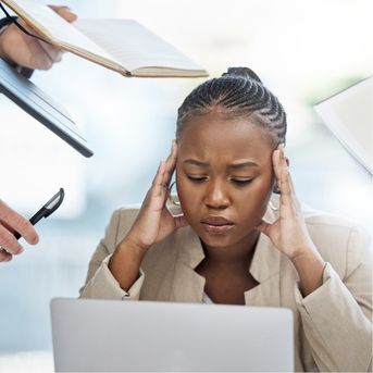 Stressed woman at laptop with people around her